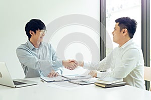 Two businessmen shaking hands as they agree on the company`s budget