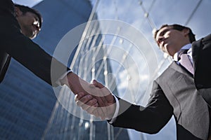 Two businessmen shaking hands in Beijing, China, view from below