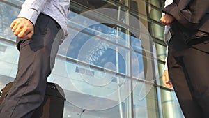 Two businessmen shaking hands of each other near office building then farewell and diverge. Business handshake outdoor