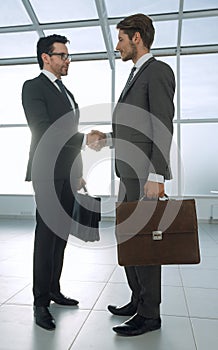 Two businessmen shaking hands in the lobby of the office