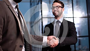 Two businessmen shaking hands and making a deal in an office corridor