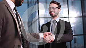 Two businessmen shaking hands and making a deal in an office corridor