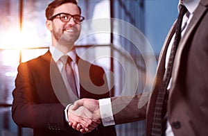 Two businessmen shaking hands and making a deal in an office corridor