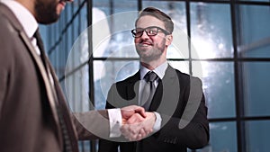 Two businessmen shaking hands and making a deal in an office corridor