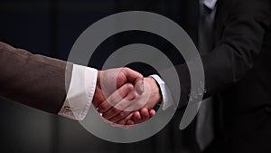 Two businessmen shaking hands and making a deal in an office corridor, partnership and interaction concept