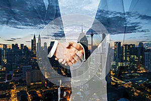 Two businessmen shaking hands on night city background. Teamwork, success and partnership concept. Double exposure