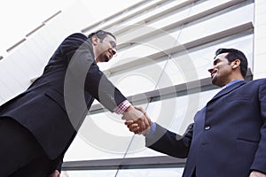 Two businessmen shaking hands outside office build
