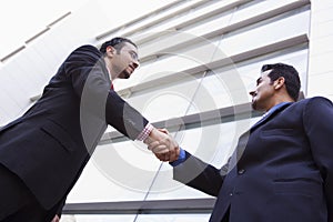 Two businessmen shaking hands outside office build