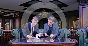 Two businessmen are sitting in beautiful apartments in suits and discussing the signing of the contract, the terms of