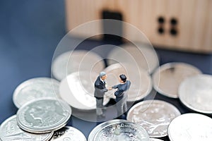 Two businessmen standing in the coin and shake hand and deal business on selling house with blurred background
