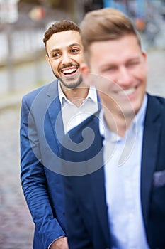 Two businessmen standing outside and laughing