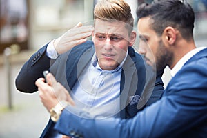 Two businessmen standing outside and looking at phone