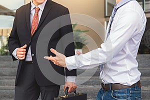 Two businessmen standing talking outside office, Business partners meeting