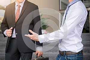 Two businessmen standing talking outside office, Business partners meeting