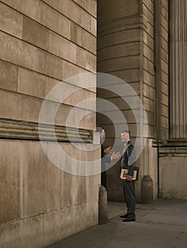 Two businessmen talking at entrance of monumental building