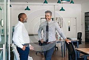 Two businessmen talking and laughing together in an office