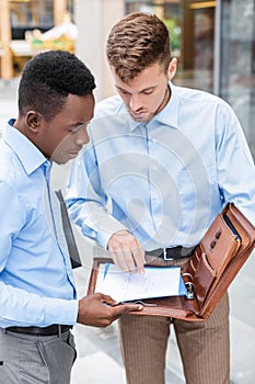 Two businessmen talking and looking at documents