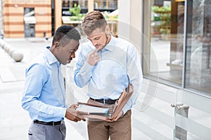 Two businessmen talking and looking at documents