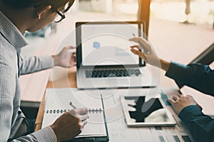 Two businessmen are together analyzing the financial data graph and pointing to the laptop computer screen