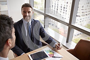 Two Businessmen Using Digital Tablet In Office Meeting