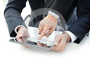 Two businessmen using tablet computer with one hand touching screen