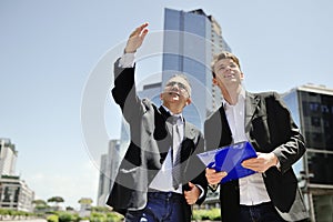 Two businessmen working about a new project on background office buildings