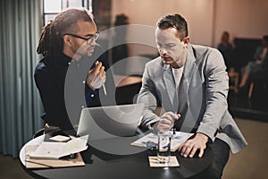 Two businessmen working over a laptop together in an office