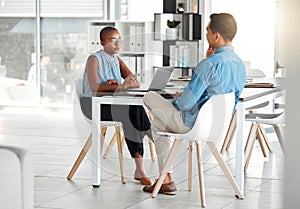 Two businesspeople having a meeting together in an office at work. Young african american businesswoman talking to an