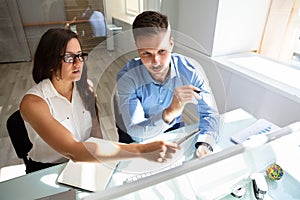 Two Businesspeople Looking At Computer Having Conversation