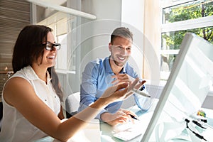 Two Businesspeople Looking At Computer Having Conversation