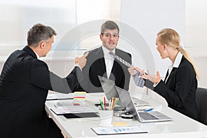 Two Businesspeople Quarreling To Young Businessman photo