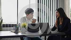 Two businesspeople sitting in office and discussing financial project.