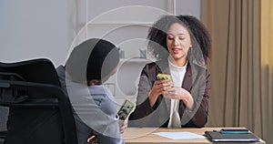 Two businesspersons afro american colleagues sitting at office table laughing celebrates success woman manager worker