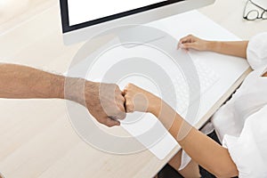 Two businesspersons fist-bumping in agreement at a meeting