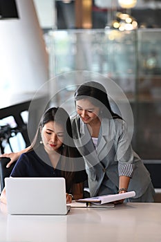 Two businesswoman colleagues discussing about new project plan at work .