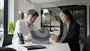 Two businesswoman using computer tablet and discussing business idea in modern office.