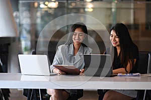 Two businesswoman working on tablet computer and discussing business data at office.