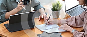 Two businesswoman working on their project and using computer tablet for checking information  in office.