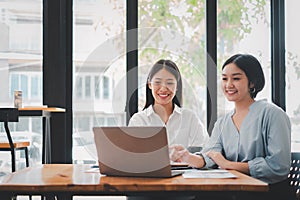 Two businesswoman working together on laptop computer