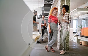 Two businesswoman working together using digital tablet pc and talking about a business project.