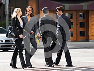 Two Businesswomen Chatting Whilst Crossing Street photo