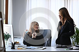 Two businesswomen discussing project together at office.