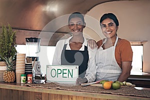 Two businesswomen making their way in the world. a businesswoman holding an open sign for her food truck.