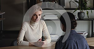 Two businesswomen negotiating and handshaking at office meeting