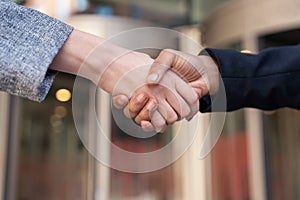 Two businesswomen in office suits shaking hands The concept of joyful business partners