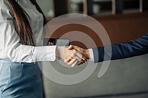 Two businesswomen shaking hands as they close a partnership, focus on hands