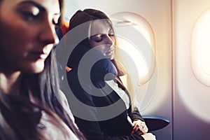 Two businesswomen sleeping in the airplane using neck cushion while going on business trip