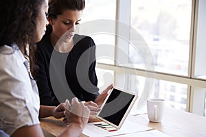 Two Businesswomen Using Digital Tablet In Office Meeting