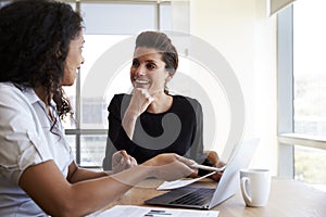 Two Businesswomen Using Laptop Computer In Office Meeting