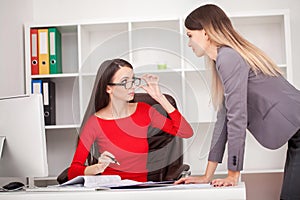 Two businesswomen working together.Girl is sitting at table in f